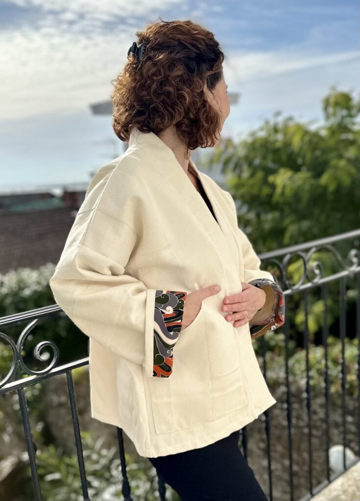 Blandine détail poche et revers manche Veste kimono BLANDINE, vue de côté, tissu beige épais, revers contrastés automne ou doré, détail poche plate.